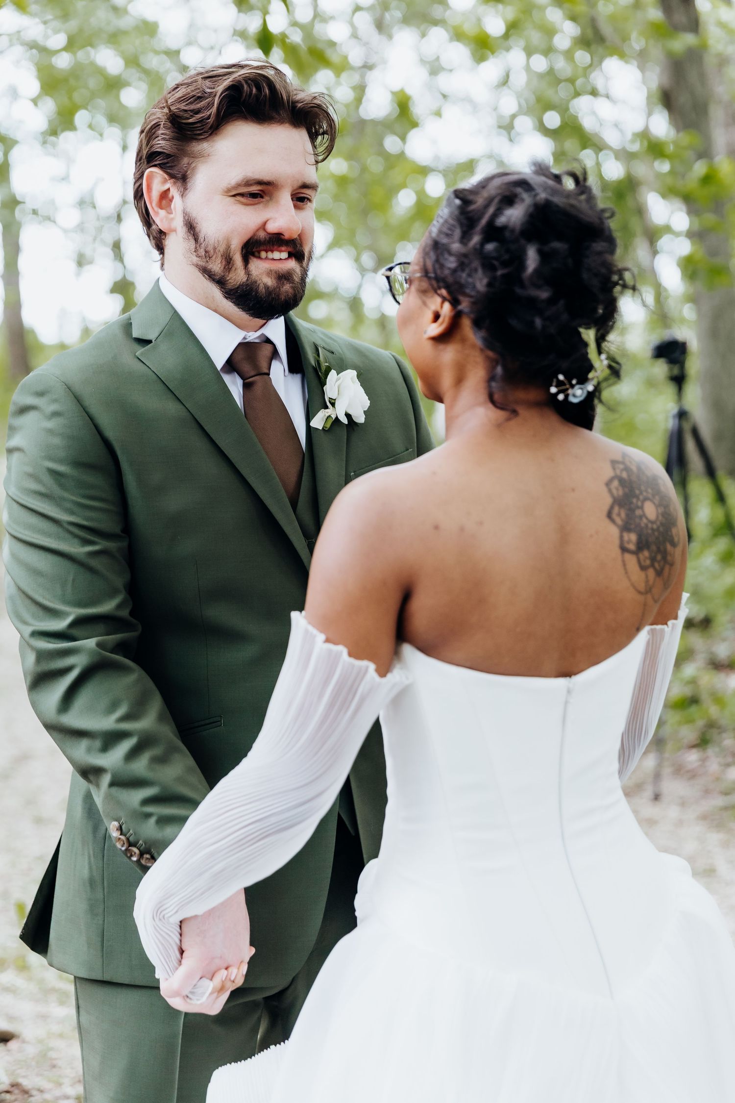 Romantic wedding couple shares intimate moments in a garden setting with the groom wearing a dark green suit.