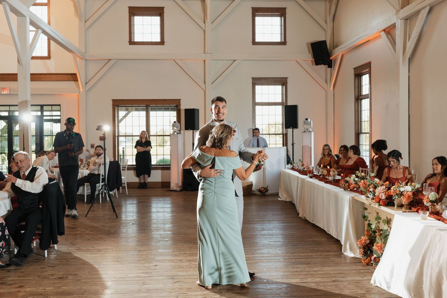 Wedding reception dance floor in white rustic venue with large windows.