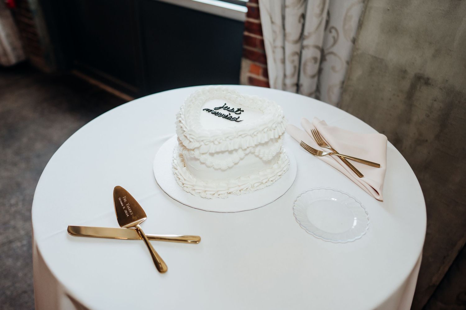 Wedding cake details with delicate white frosting and gold utensils on a white tablecloth.