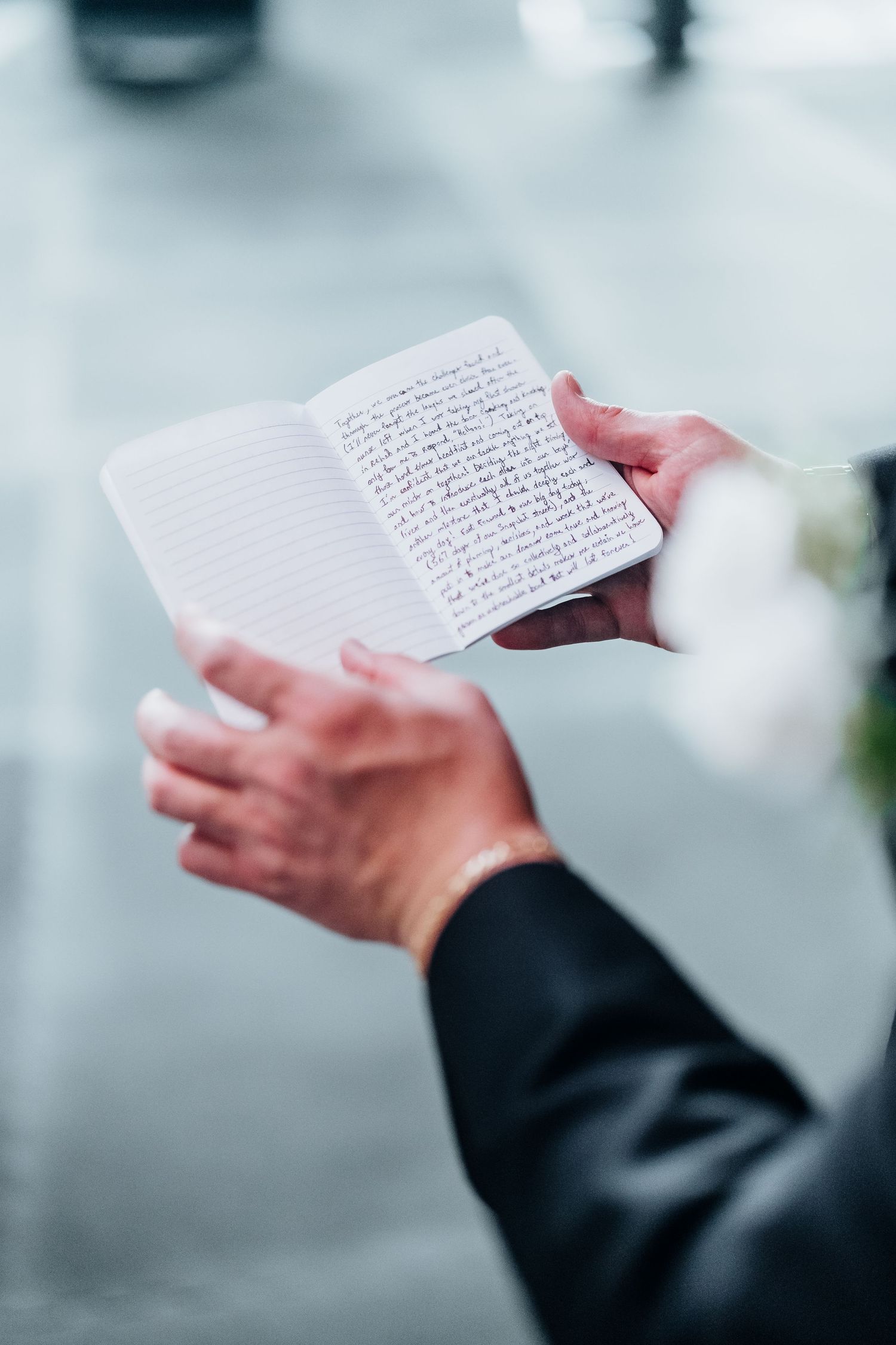 Hands holding a handwritten letter or note card against a blurred background.