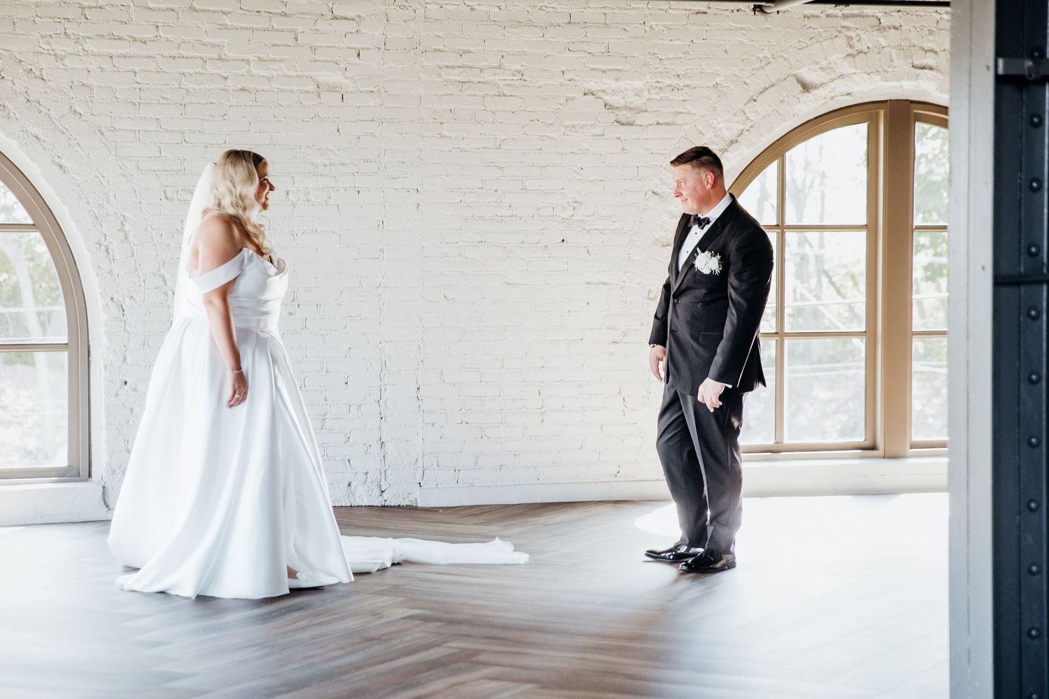 Wedding couple shares a romantic moment in a bright, minimalist white brick venue.