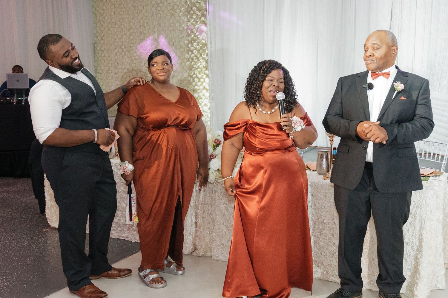 Wedding reception celebration with guests in formal attire dancing in copper-colored dresses.