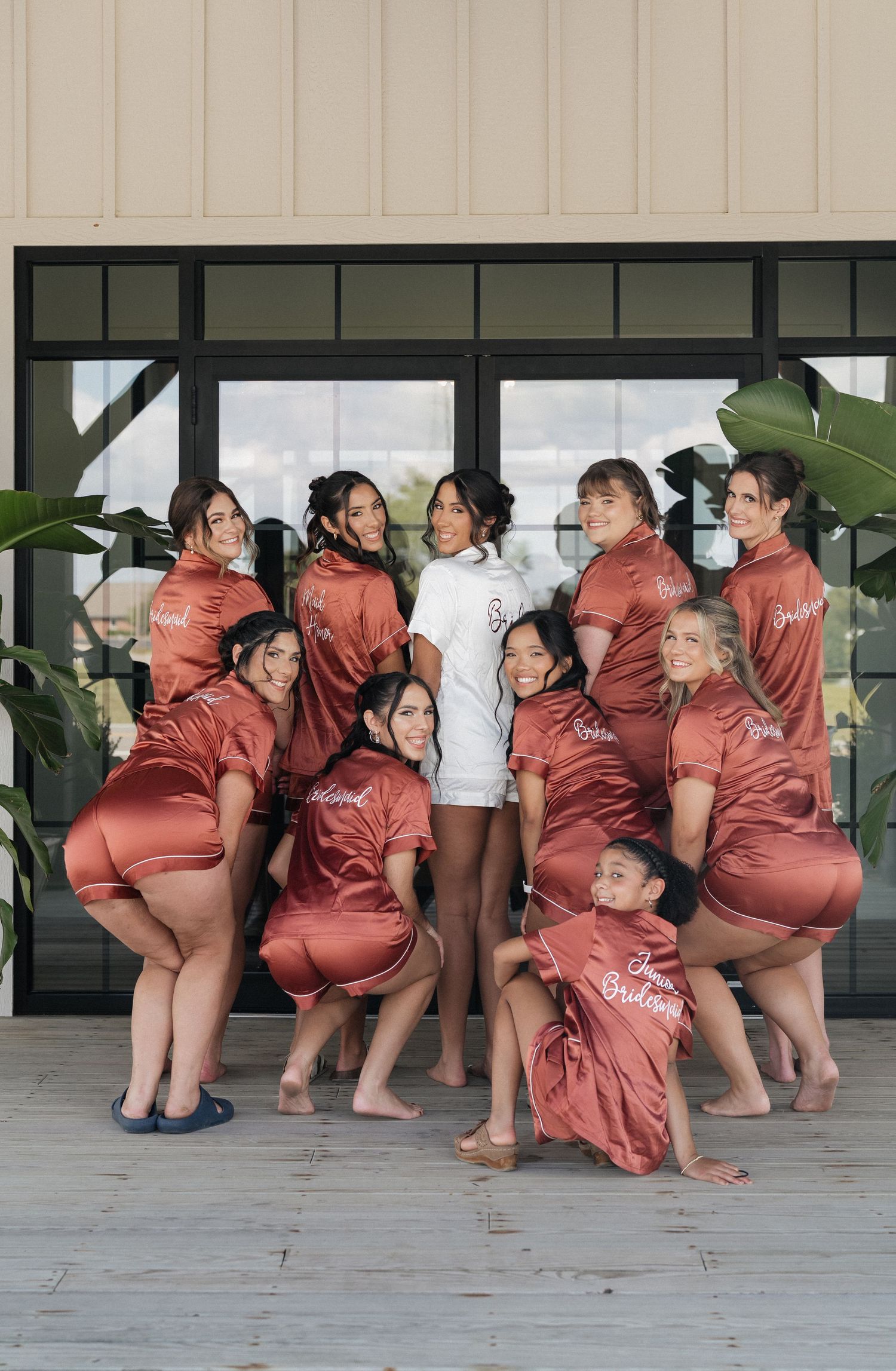 Bridesmaids in matching dusty rose satin dresses posing playfully for a photo.