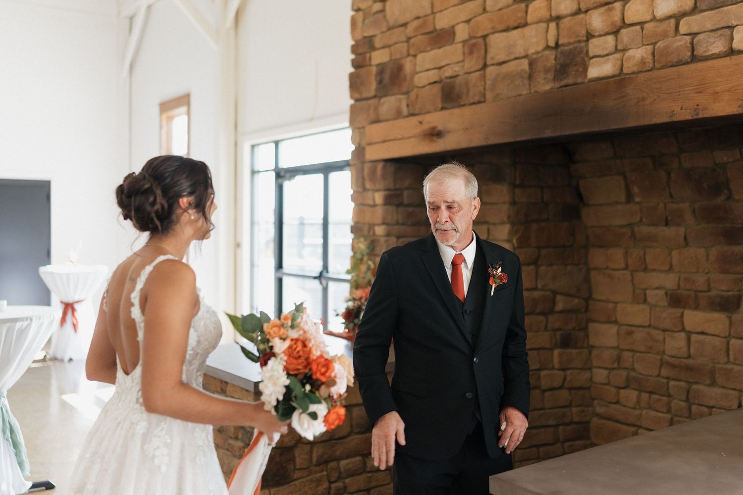 Wedding party gathered in rustic brick-walled venue space.