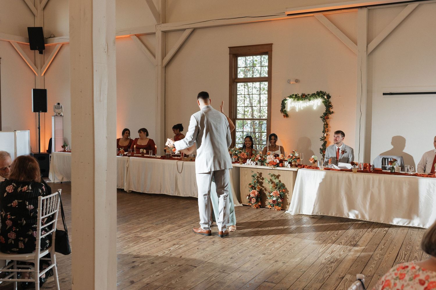 Bright white reception venue with high ceilings and rustic wooden beams.