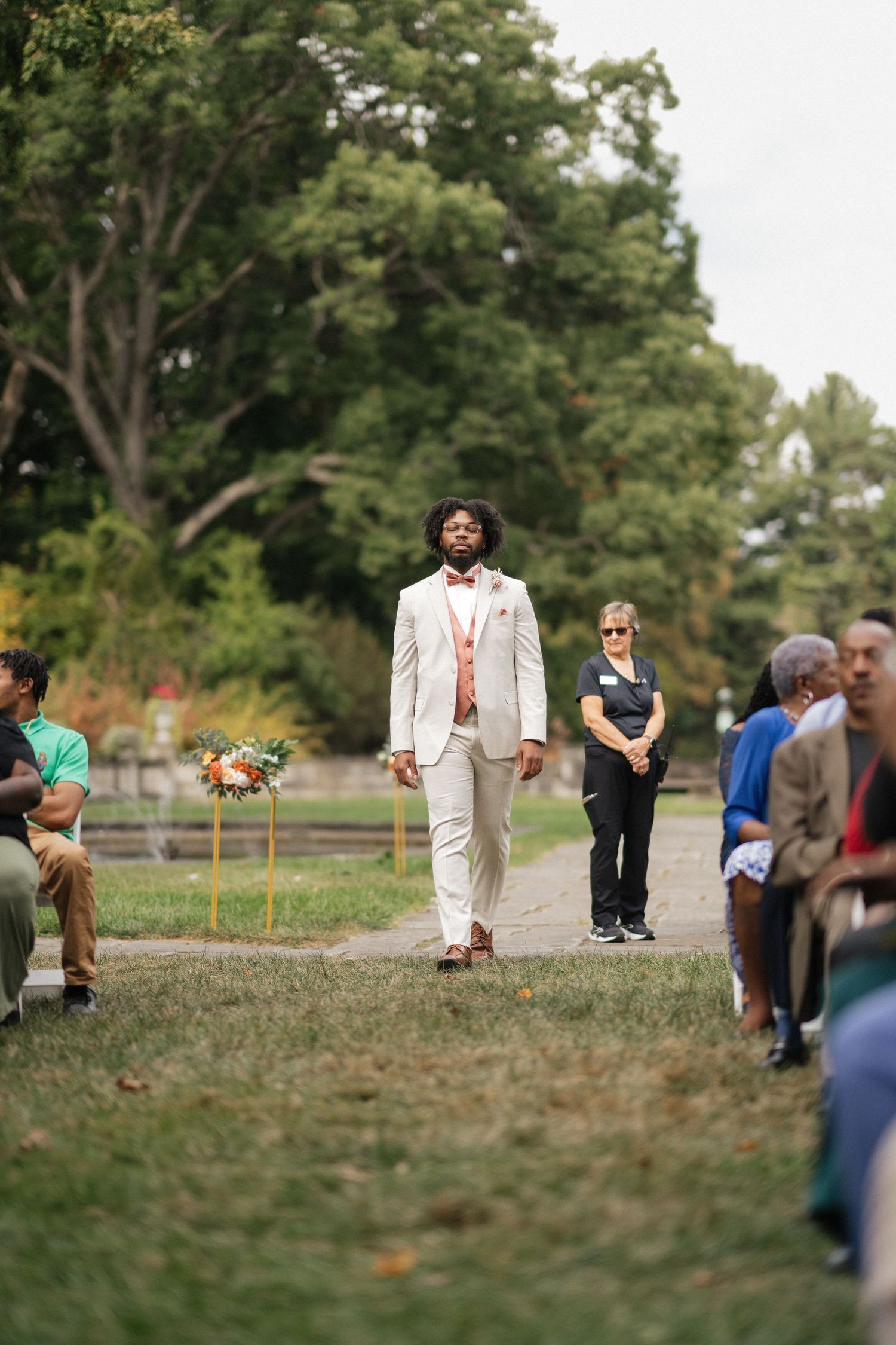 Wedding processional sequence showing attendants walking across a grassy outdoor venue.