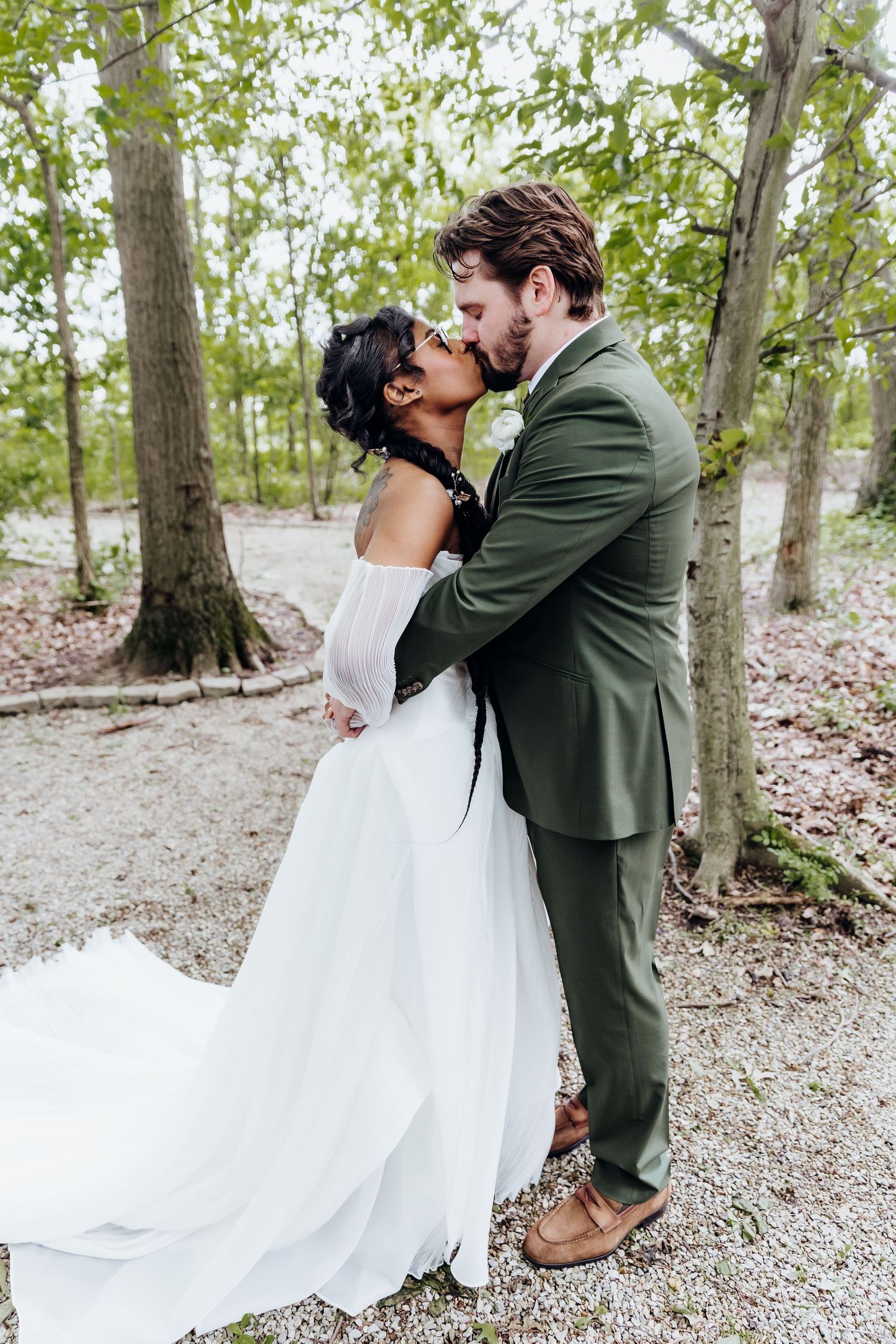 Romantic wedding couple shares intimate moments in a wooded setting with natural light filtering through trees.