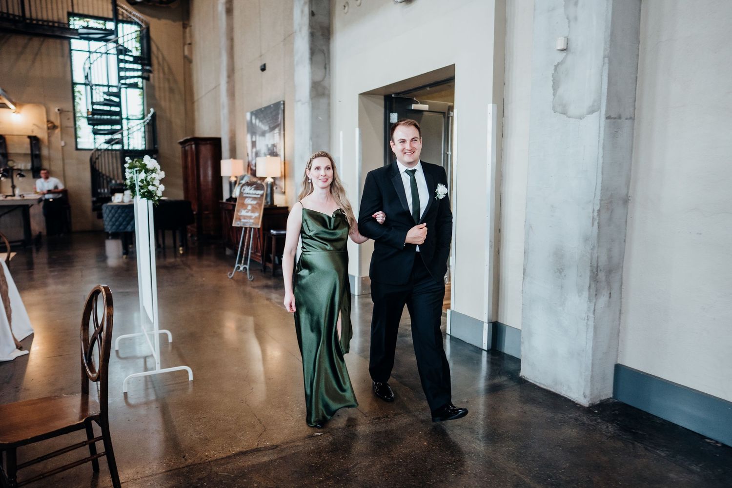 Wedding party members walking through modern industrial venue hallway.