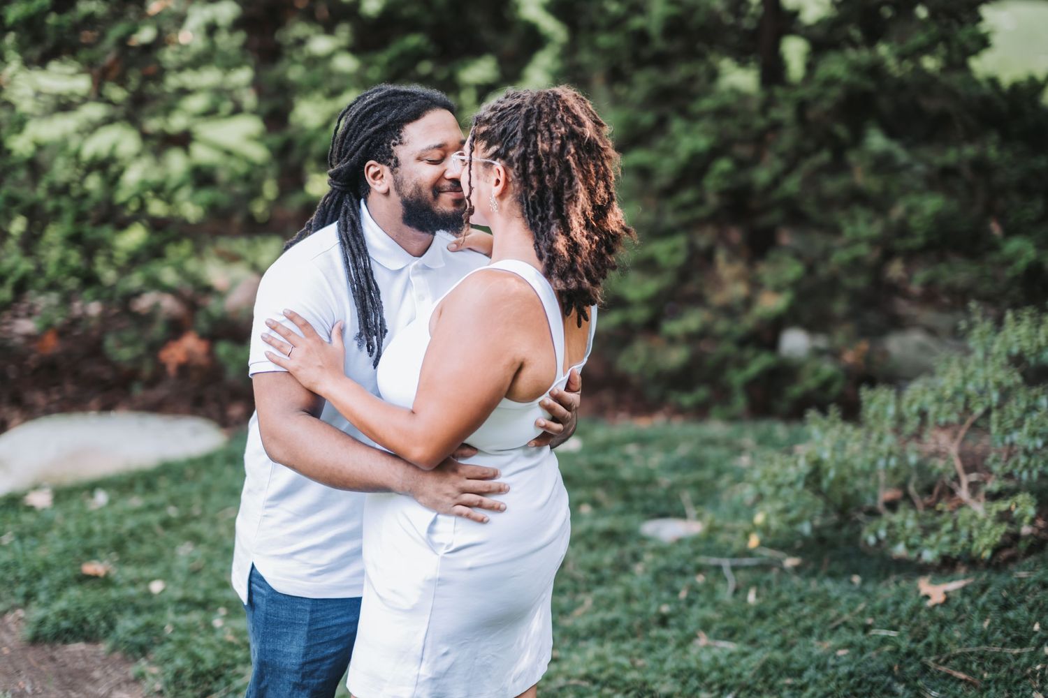 A joyful embrace captured in a garden setting during a photo session.