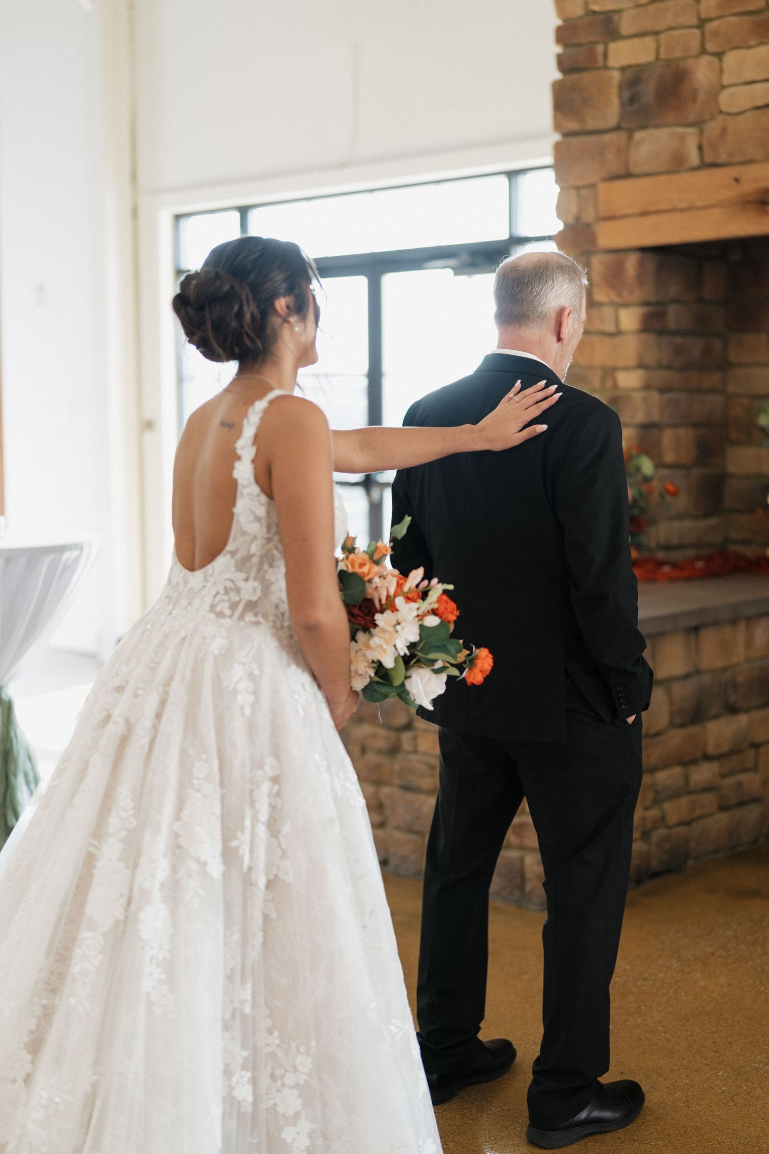 Back view of bride in lace ballgown with father before walking down the aisle.