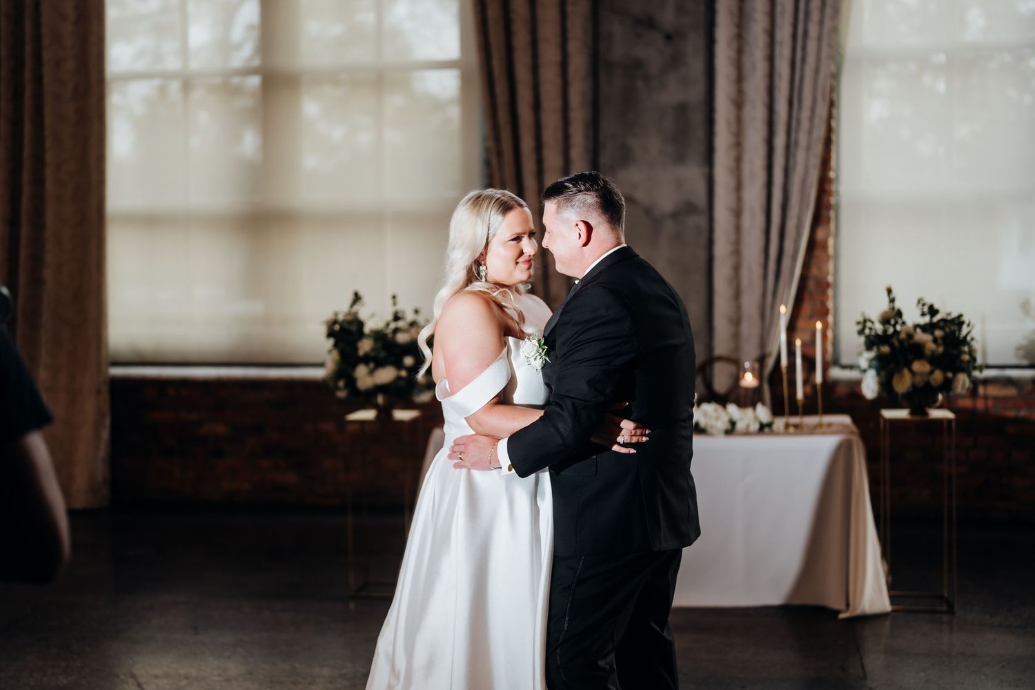 Romantic wedding portraits in a light-filled industrial venue with exposed brick walls.
