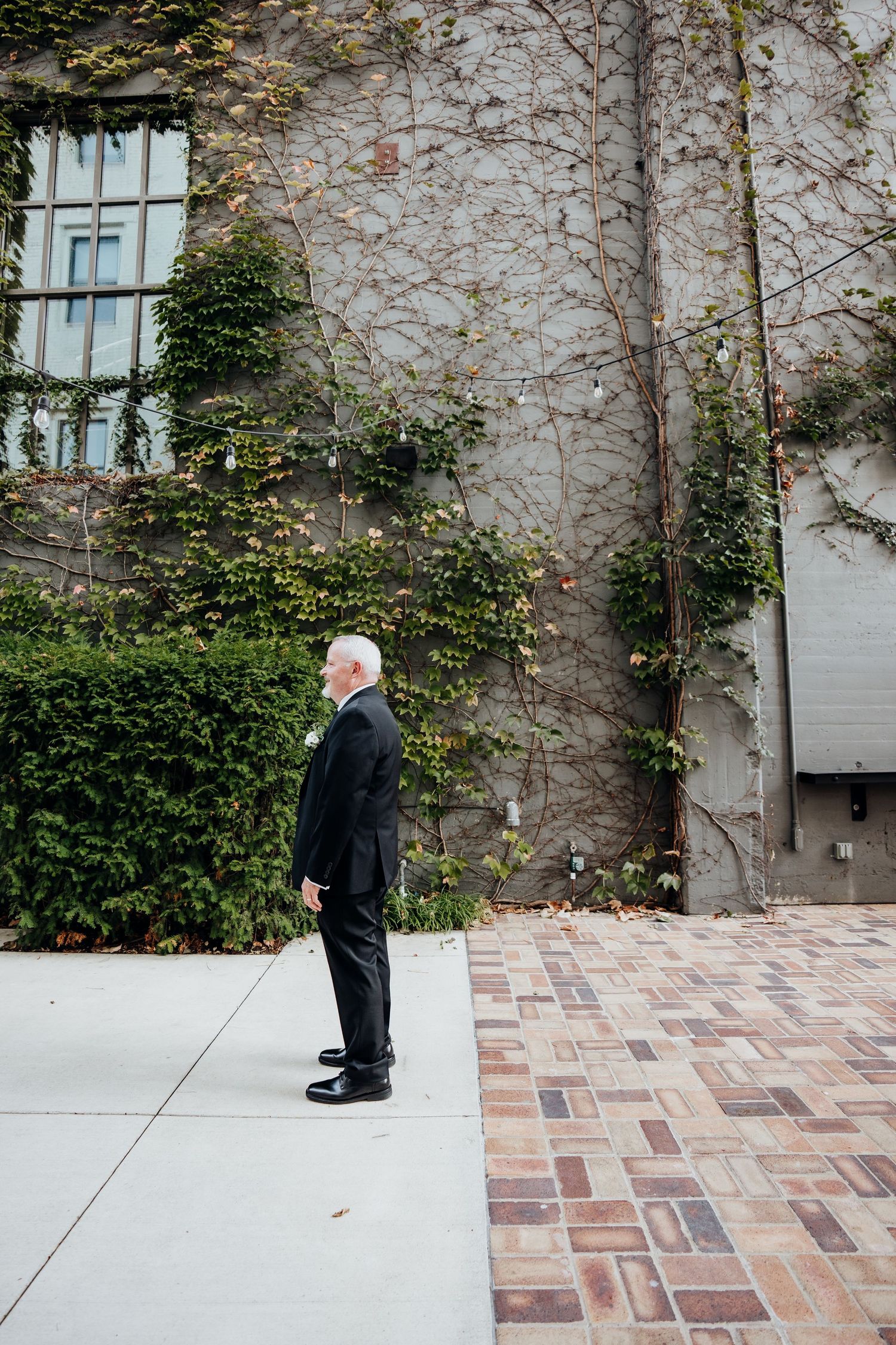 A sequence of photos showing someone in a suit walking across a brick courtyard with ivy-covered walls.