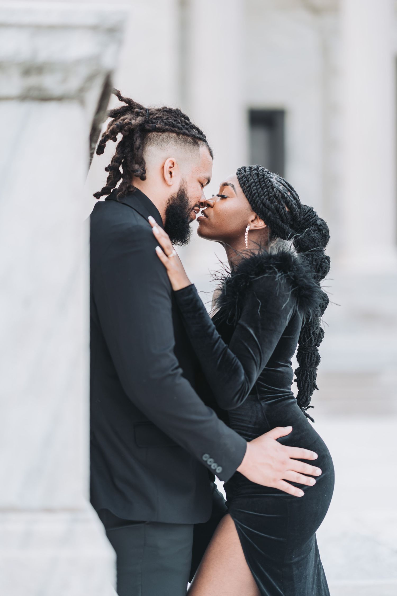 A couple embraces passionately in formal attire, with the woman wearing a black velvet dress.
