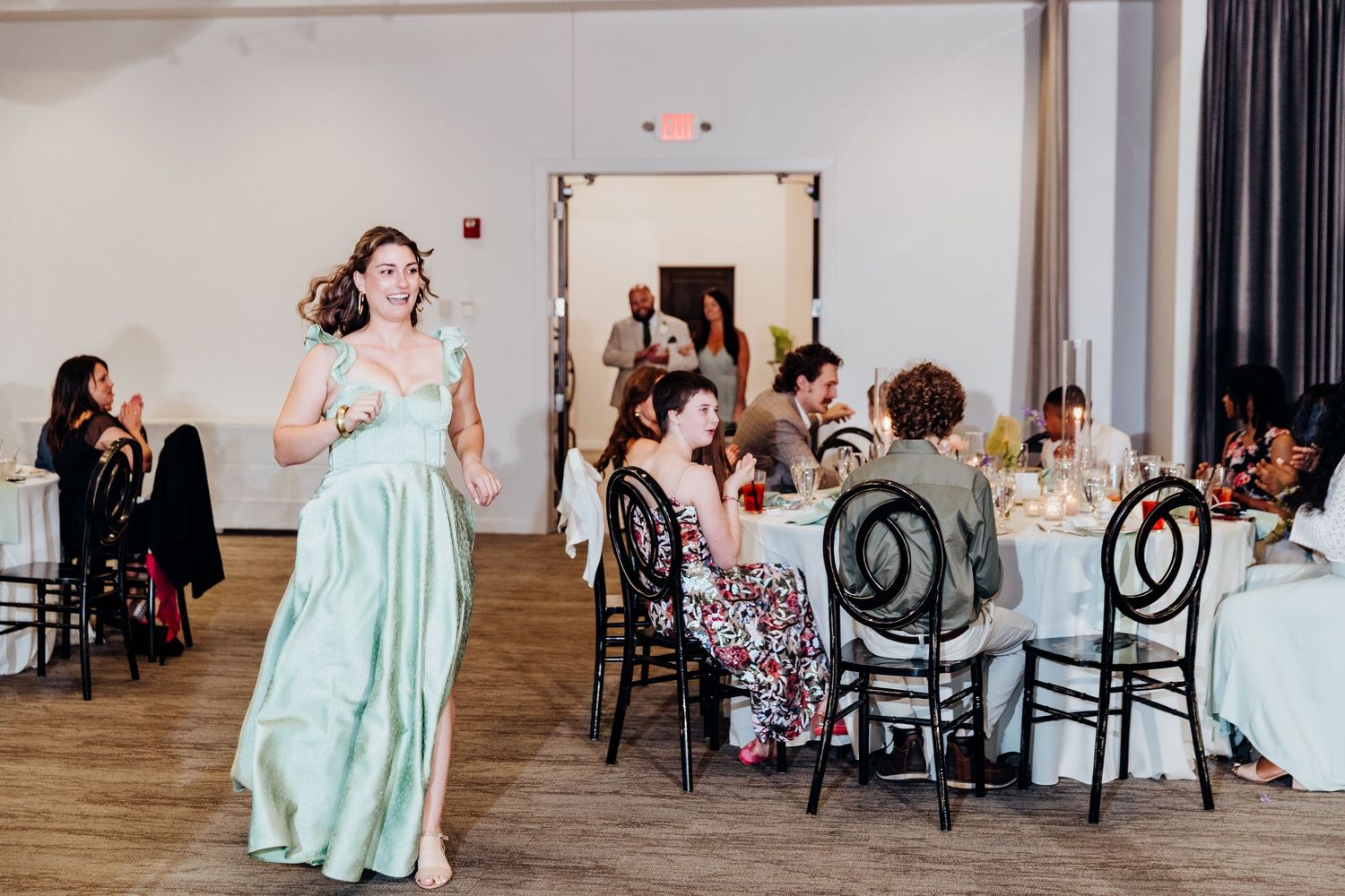 Wedding reception setup in modern venue with wooden floors and elegant black chairs.