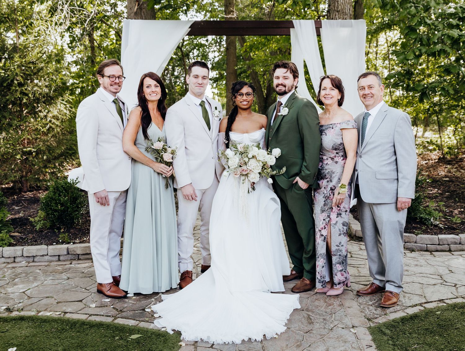 Wedding group photo with bridal party in coordinated sage green and grey attire.