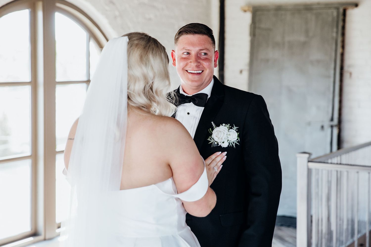 Wedding couple shares an intimate moment in an elegant white brick interior space.