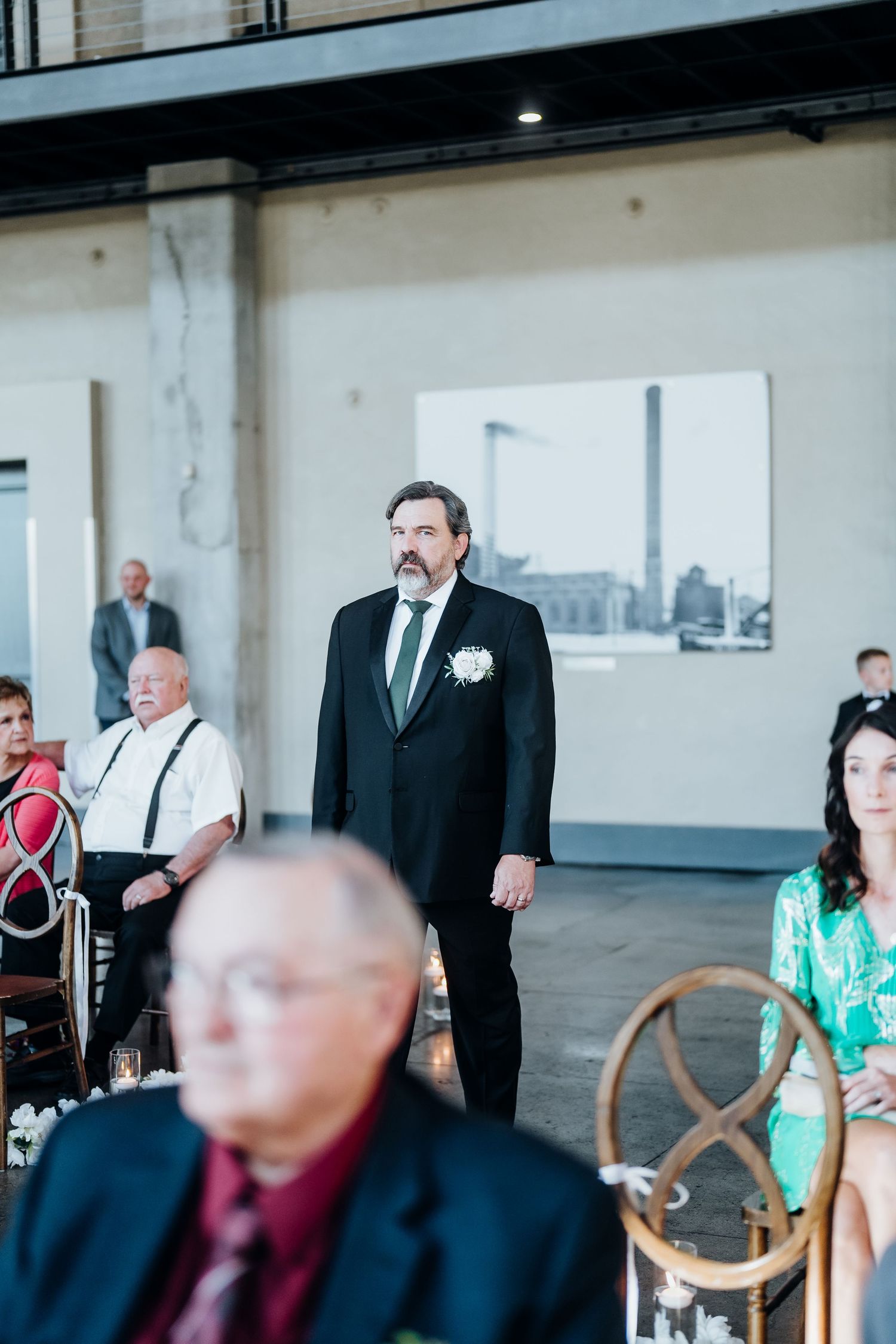 Wedding ceremony setup in an industrial space with vintage chairs and natural lighting.