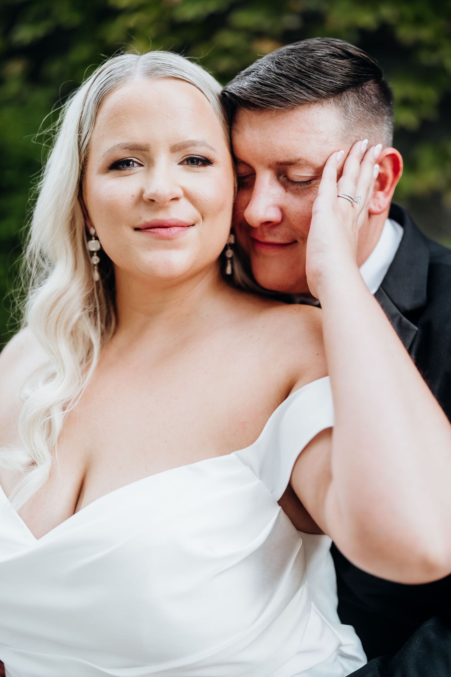 Intimate wedding portrait of couple sharing tender moment outdoors.