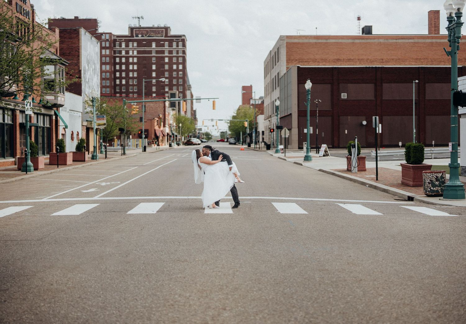 A wide shot of a couple dancing in the middle of a city street with tall buildings in the background.