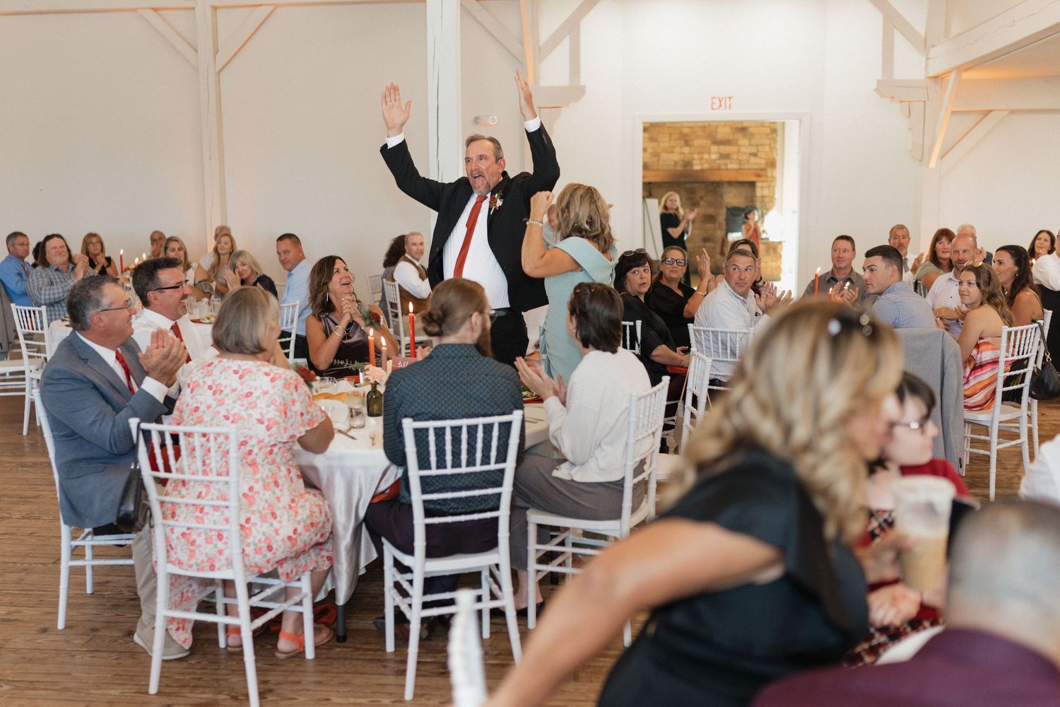 Wedding reception venue with white chairs and rustic barn interior decor.