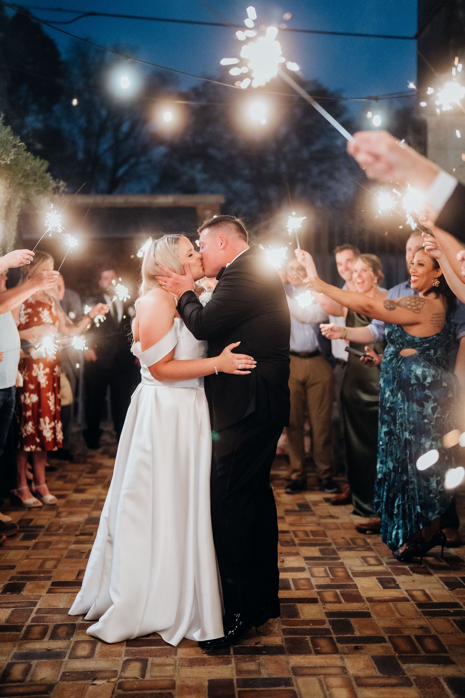 Couple dancing surrounded by guests holding sparklers creating a magical nighttime atmosphere.