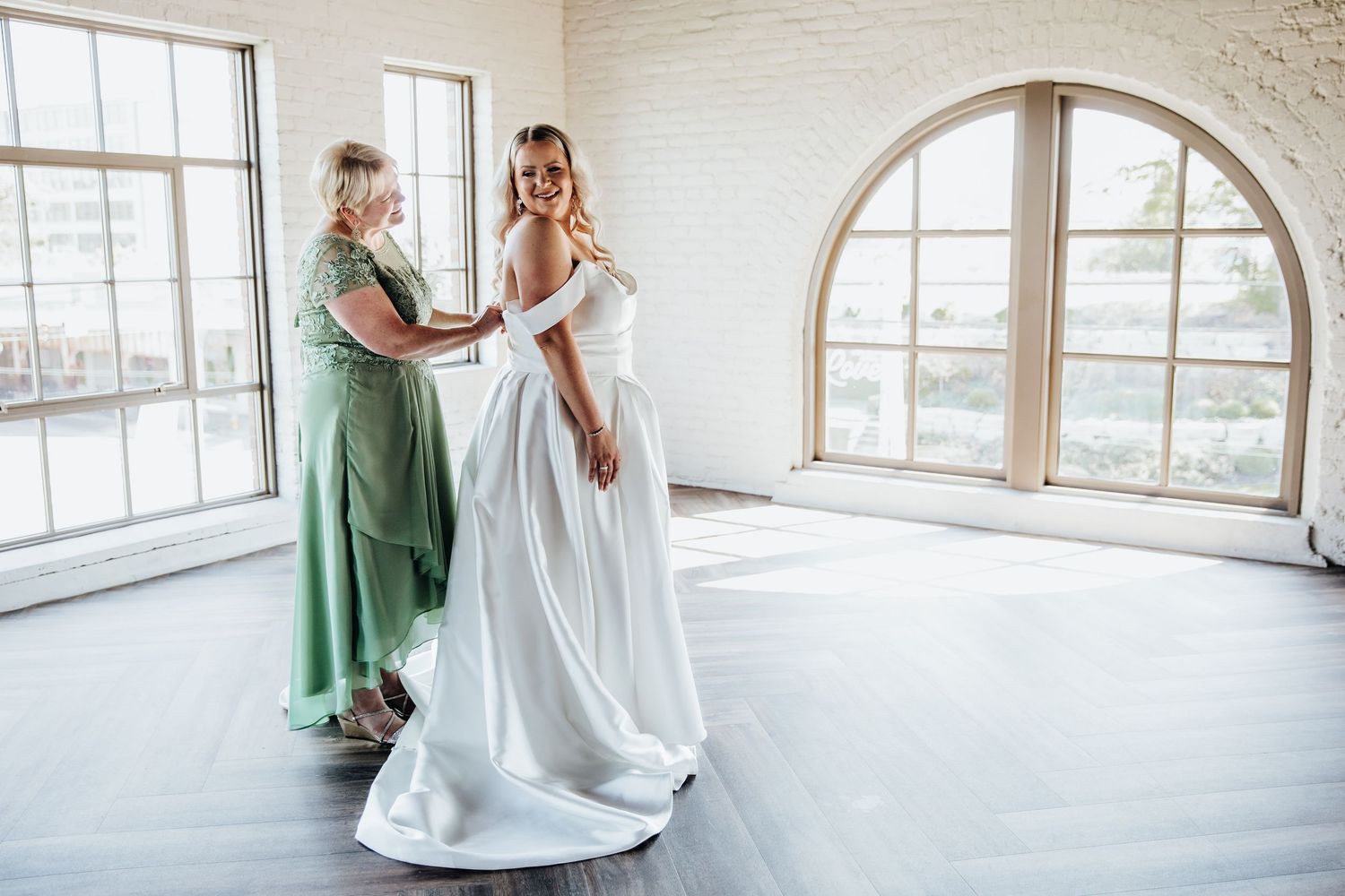 Bright sunlit wedding venue with white brick walls and arched windows.