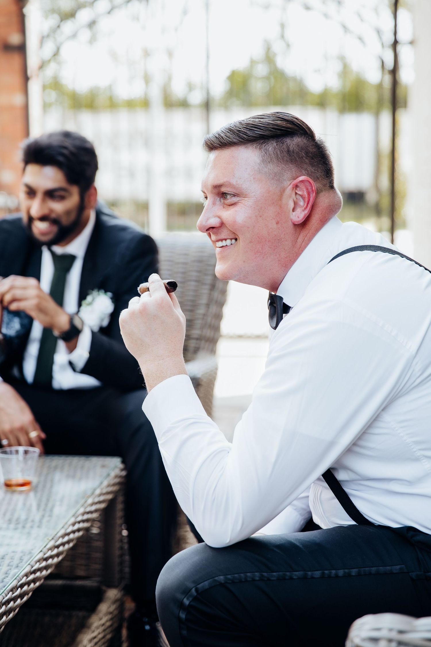 Wedding party members in formal attire relaxing on outdoor patio furniture.