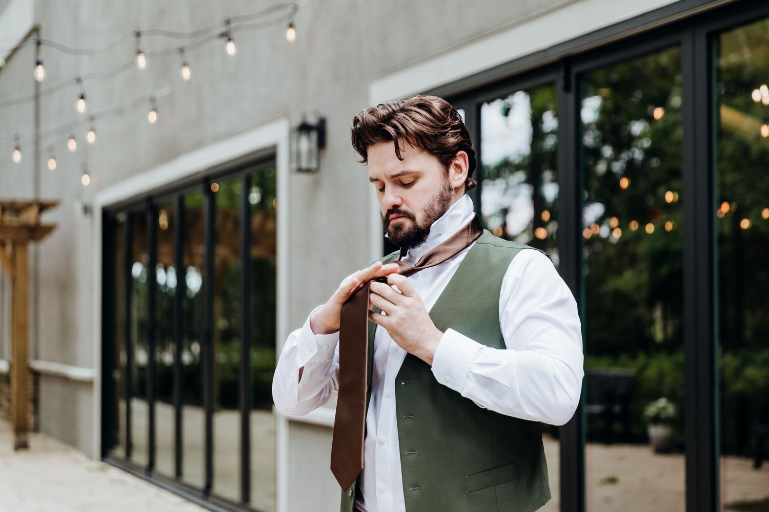 Wedding couple shares intimate moments during outdoor reception under string lights at dusk.