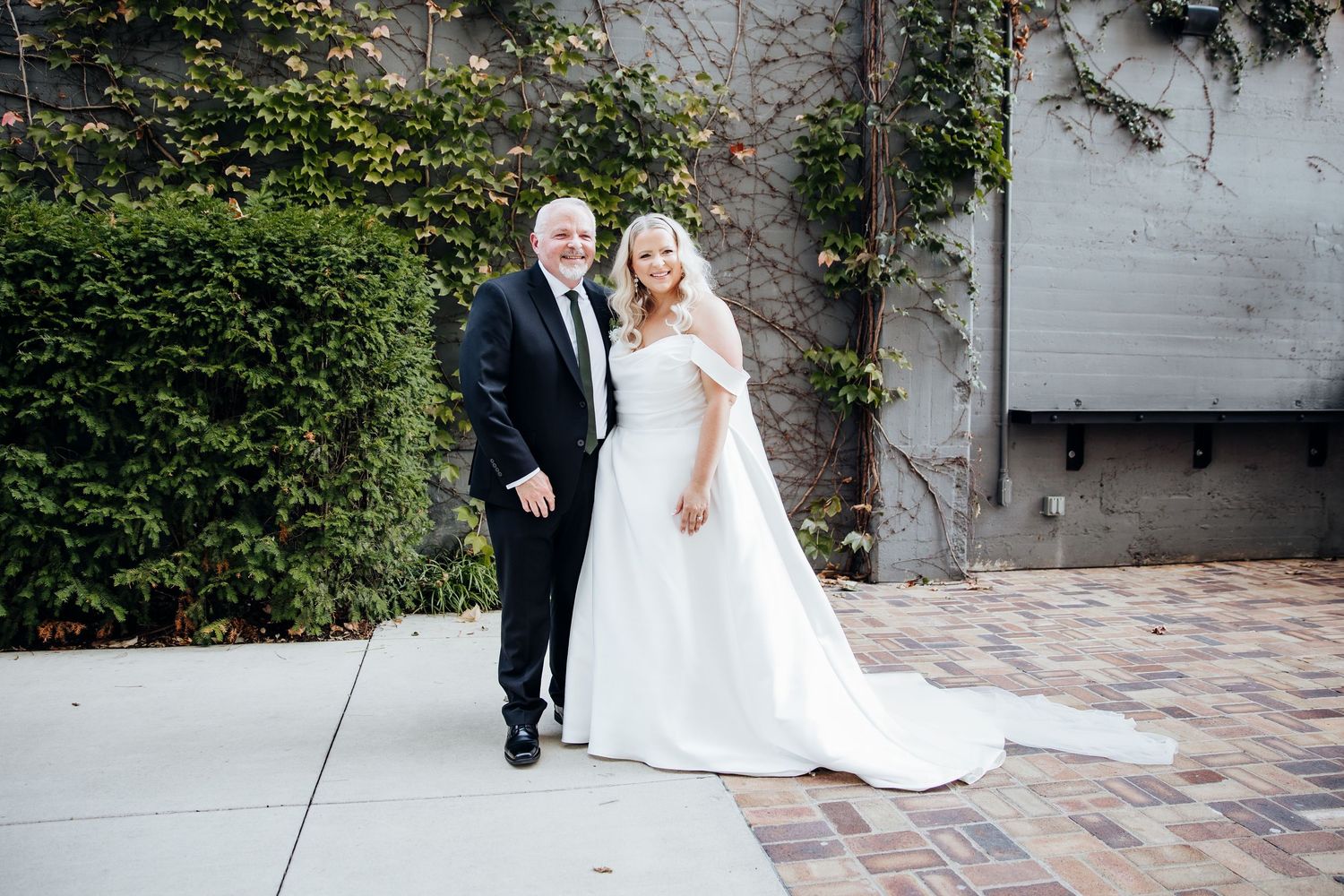 Wedding couple poses for romantic portraits along a garden pathway with stone walls.