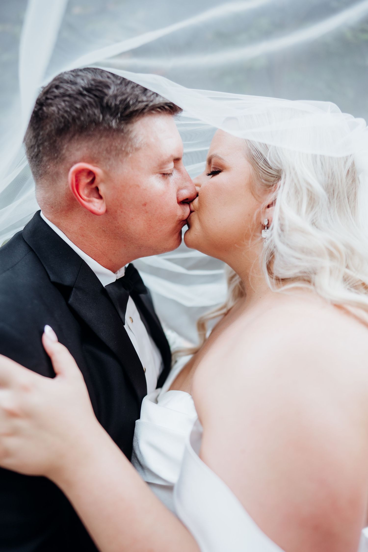 Close-up artistic wedding photo of a couple sharing an intimate moment under a flowing veil.