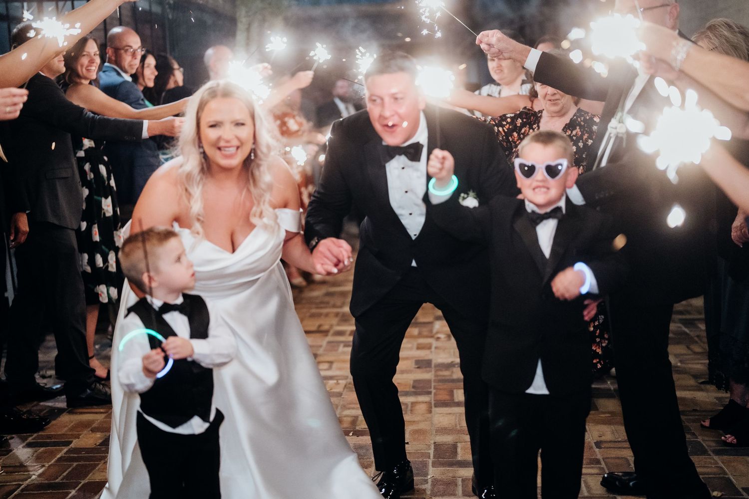 Wedding party celebrating with sparklers at night creating a magical light display.