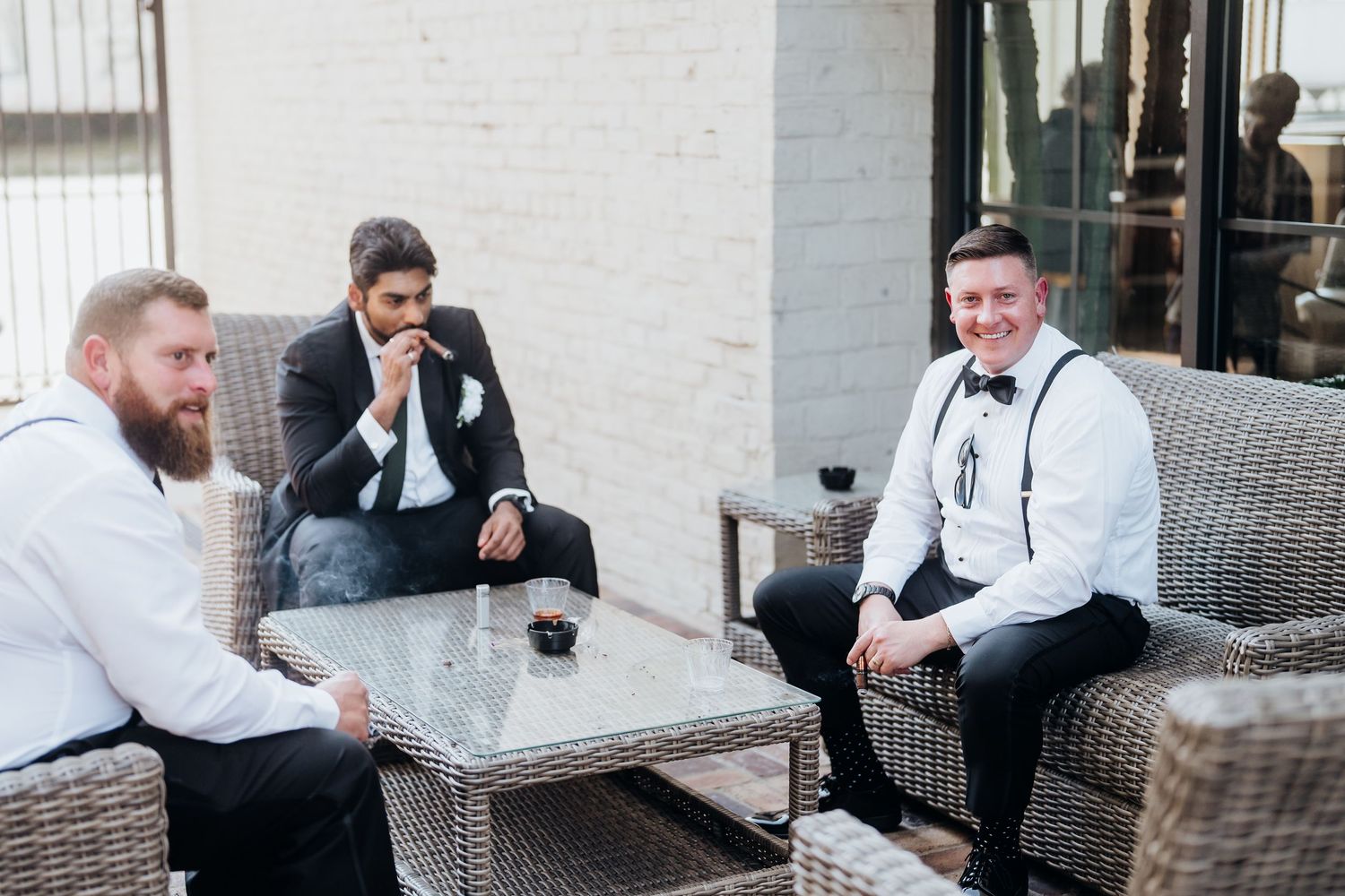 Groomsmen relaxing and chatting on outdoor patio furniture.