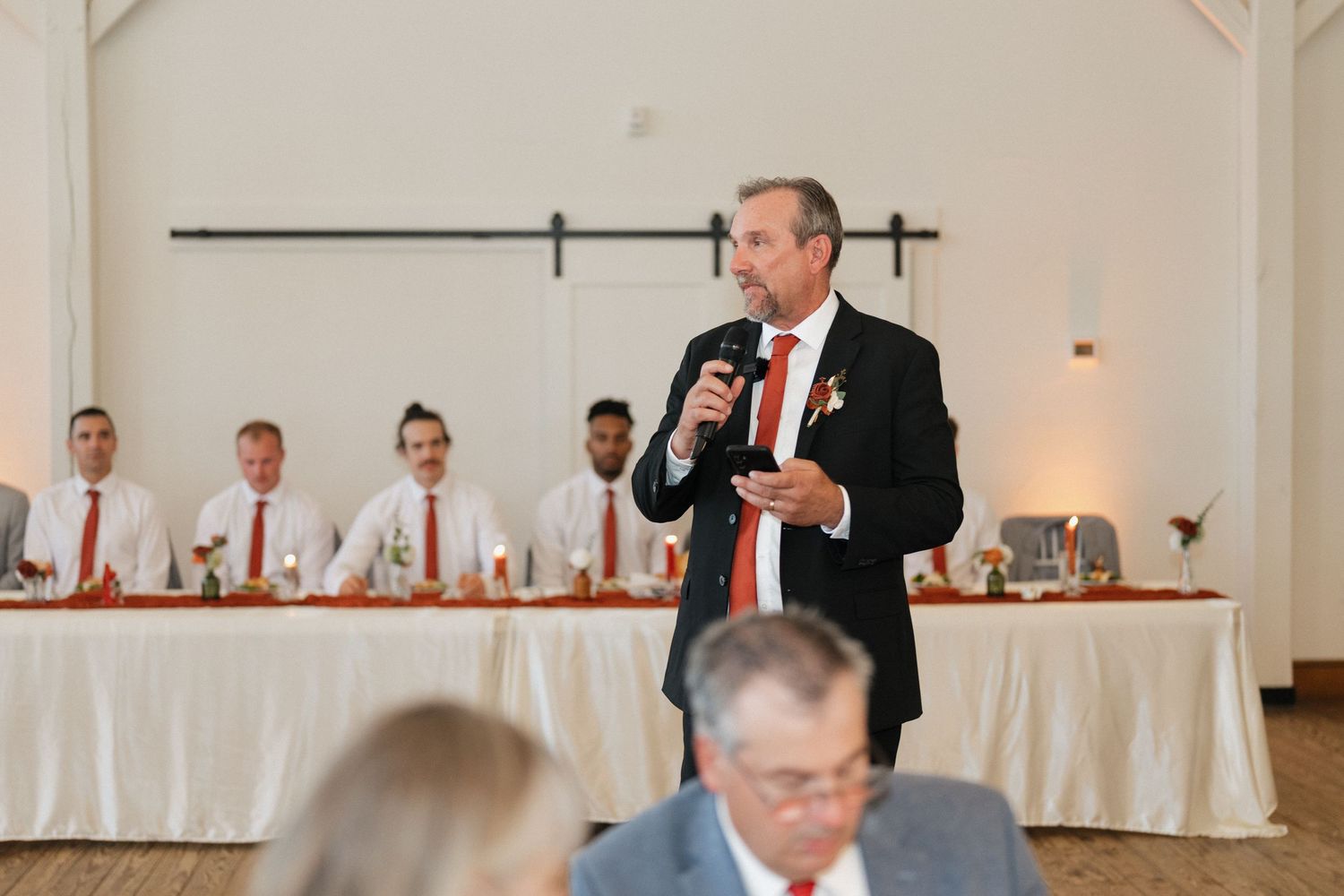 Wedding reception setup in white banquet hall with elegant table settings and decor.