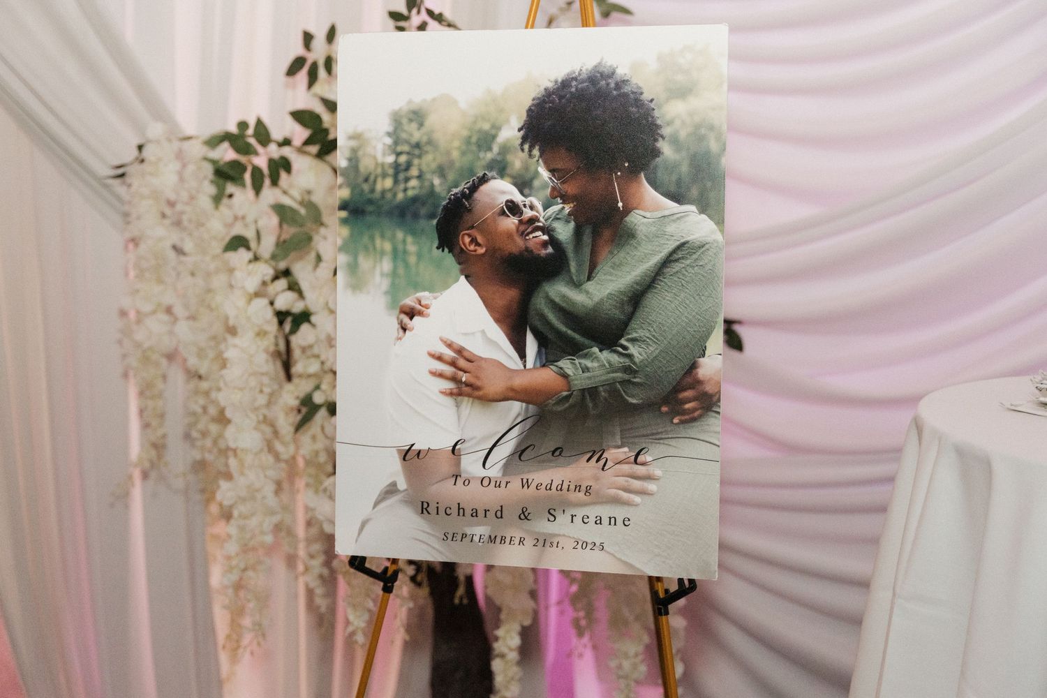 Engagement photo displayed on canvas at wedding reception with draped fabric backdrop.