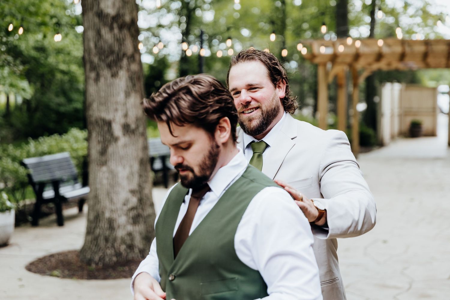 A couple shares a romantic moment in a garden setting wearing green and white formal attire.