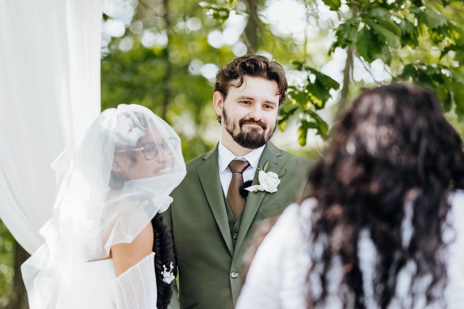 A wedding ceremony moment captured outdoors with greenery in the background.