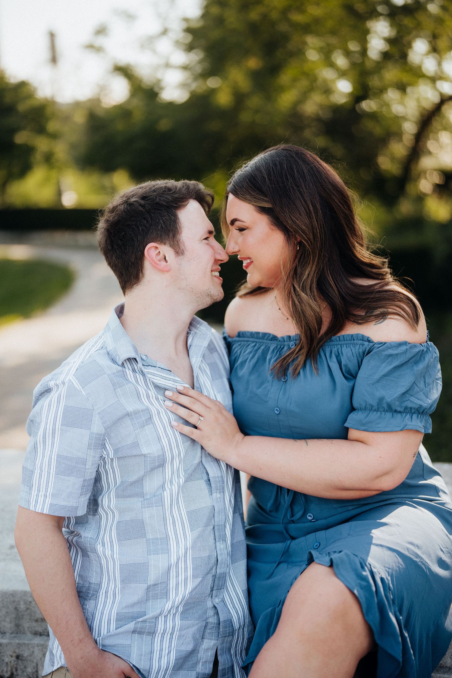 A couple shares a tender moment while sitting outdoors in casual summer clothing.