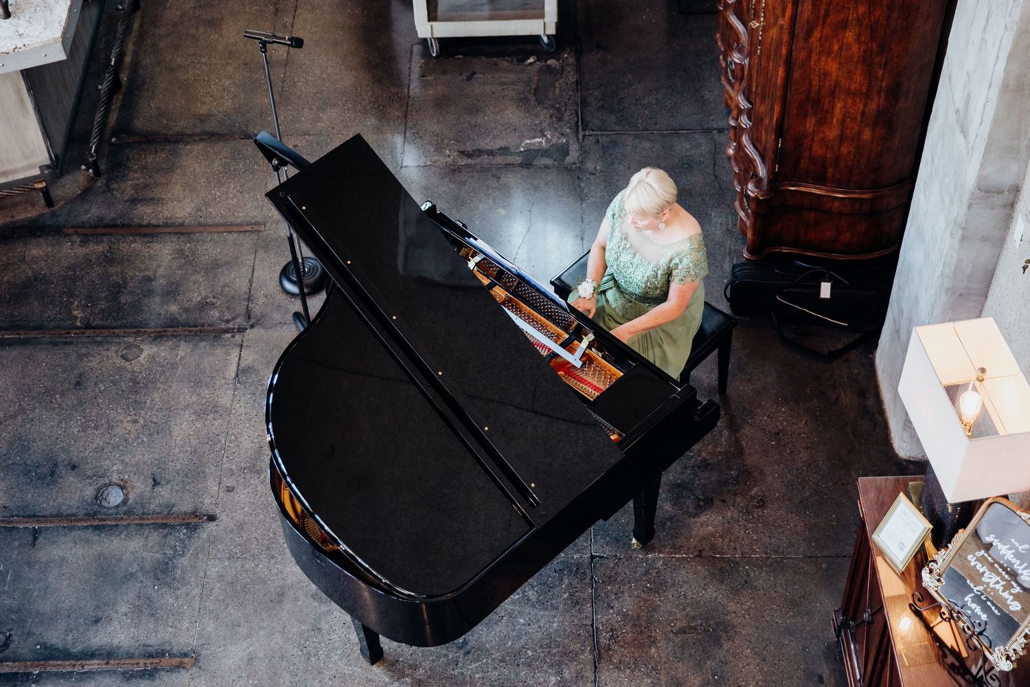 Artistic overhead shots of a black grand piano in a rustic industrial space.