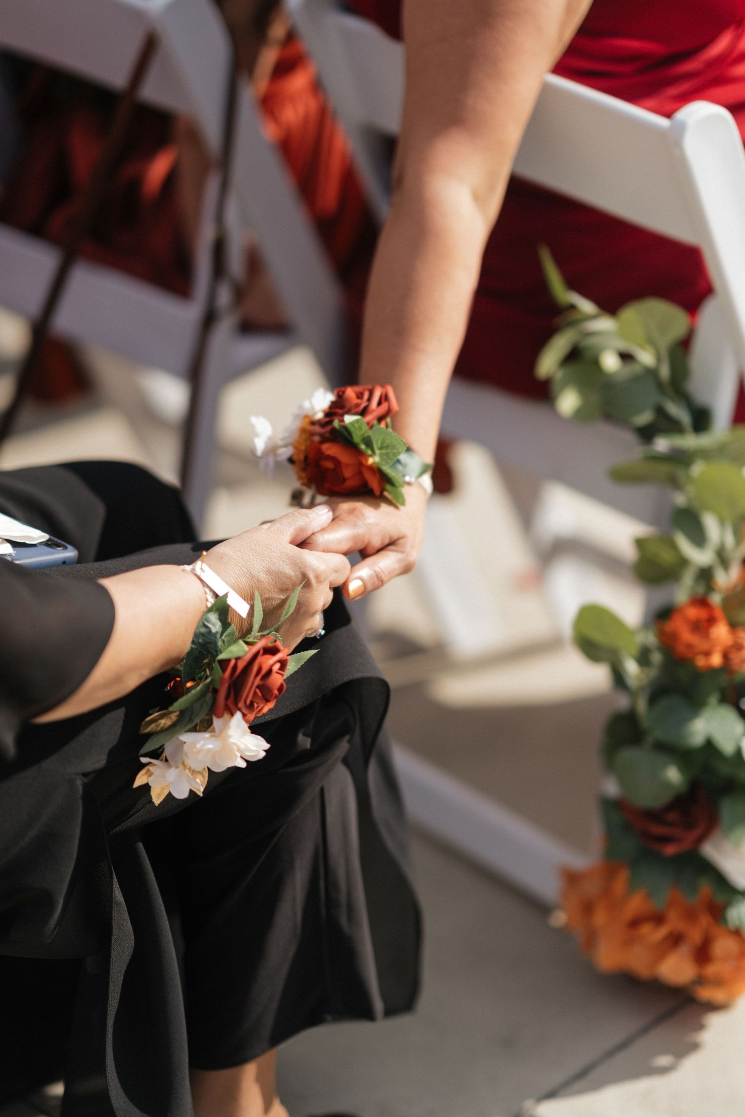 Close-up of hands holding delicate wedding flowers against black formal attire.
