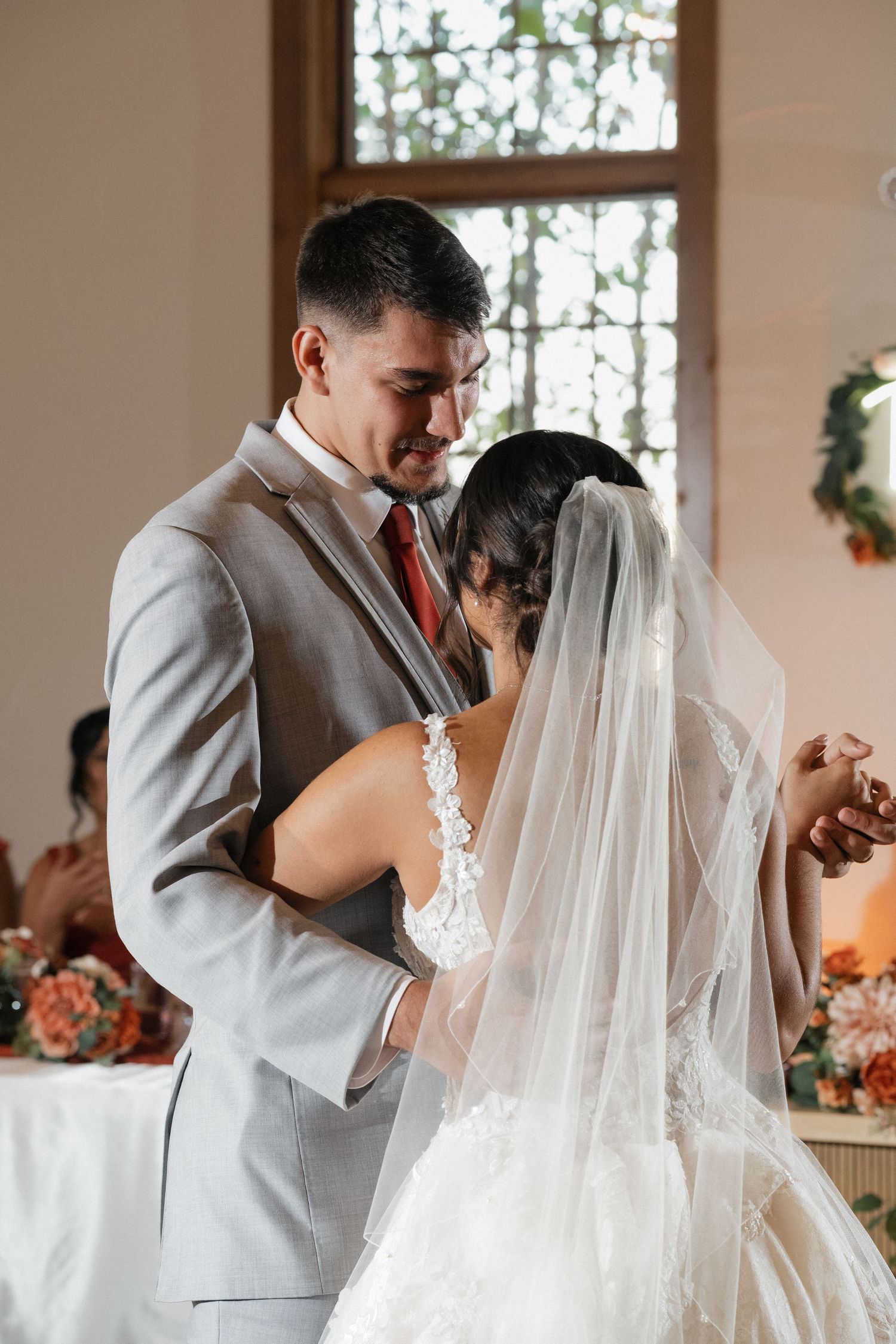 A couple shares an intimate moment during their first look in a sunlit room.