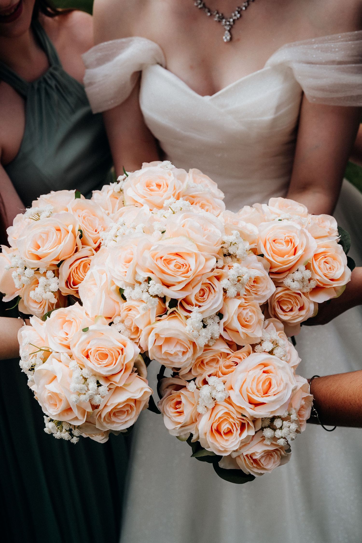 Close-up of peachy pink rose bouquet against white wedding dress.