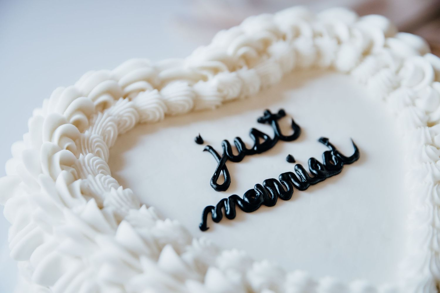 Close-up detail of white wedding cake frosting with black script text.