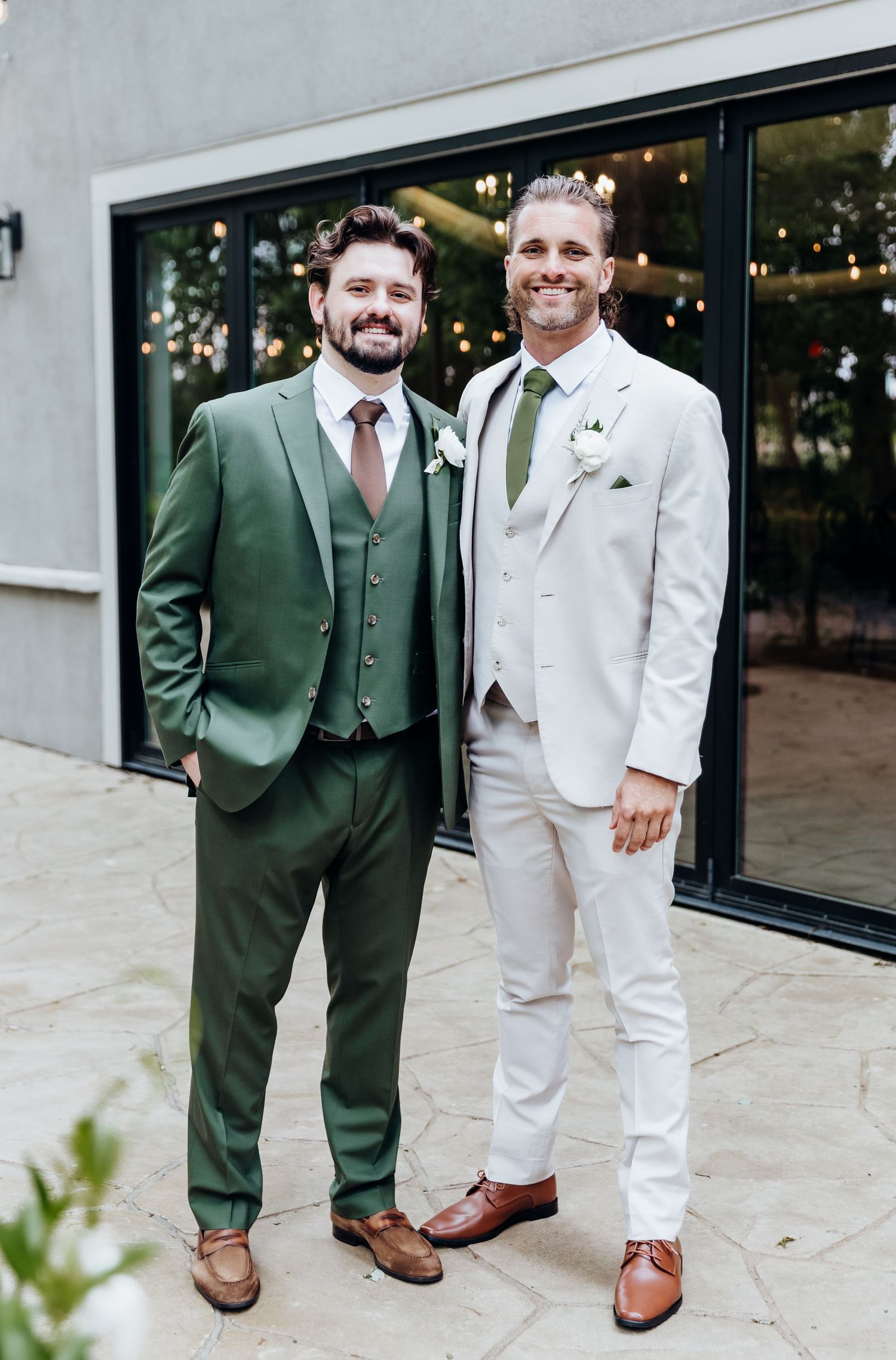 Wedding party members in contrasting green and white suits standing together on stone patio.