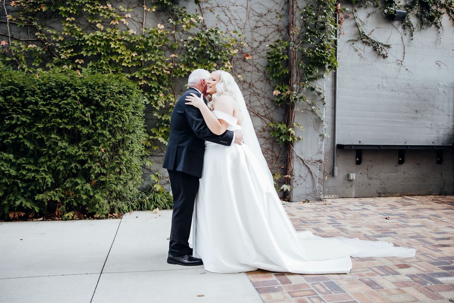 Romantic wedding couple poses together in an outdoor garden setting with lush greenery.