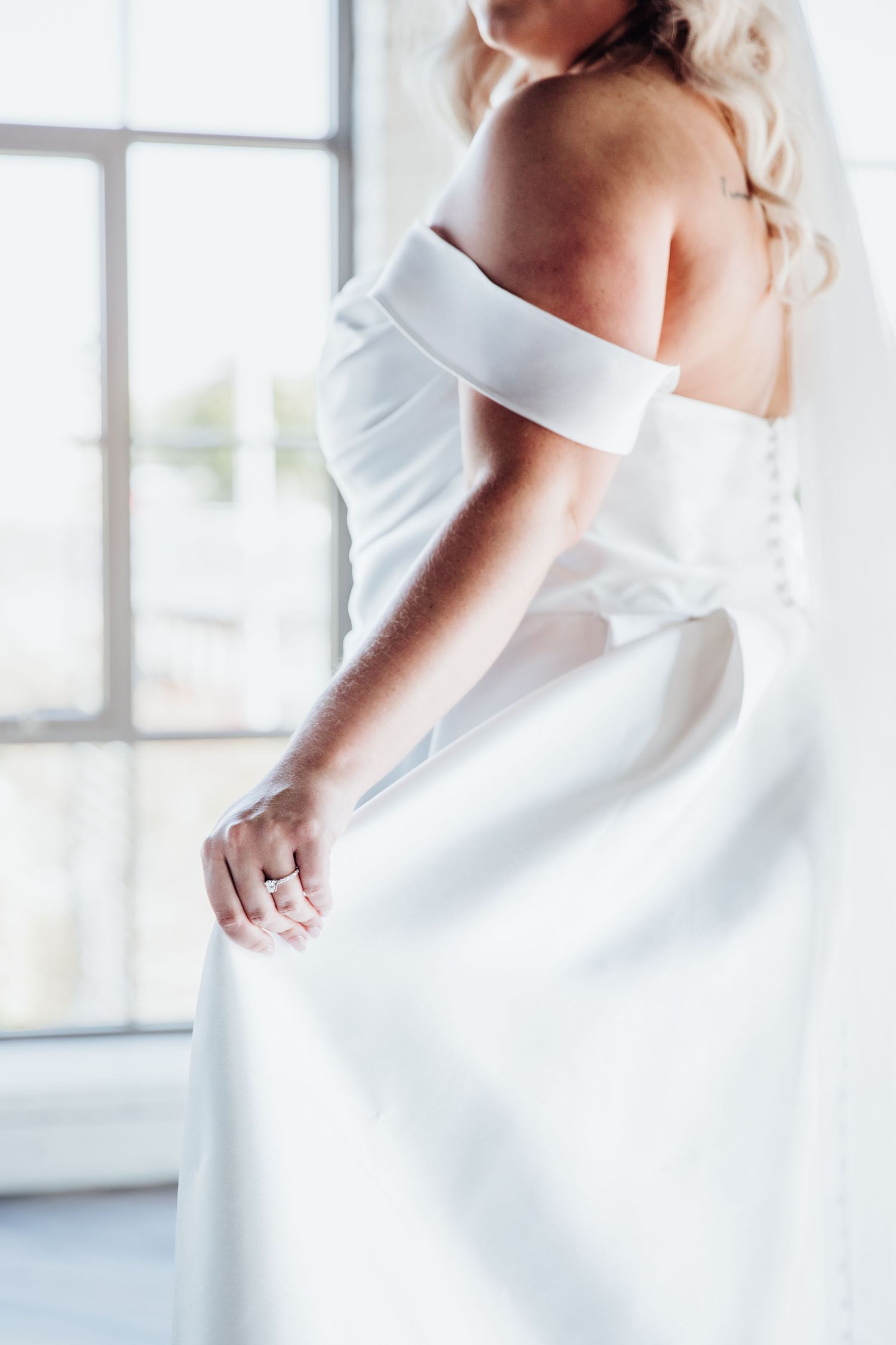 Close-up details of a white wedding dress showing off its elegant fabric and design.