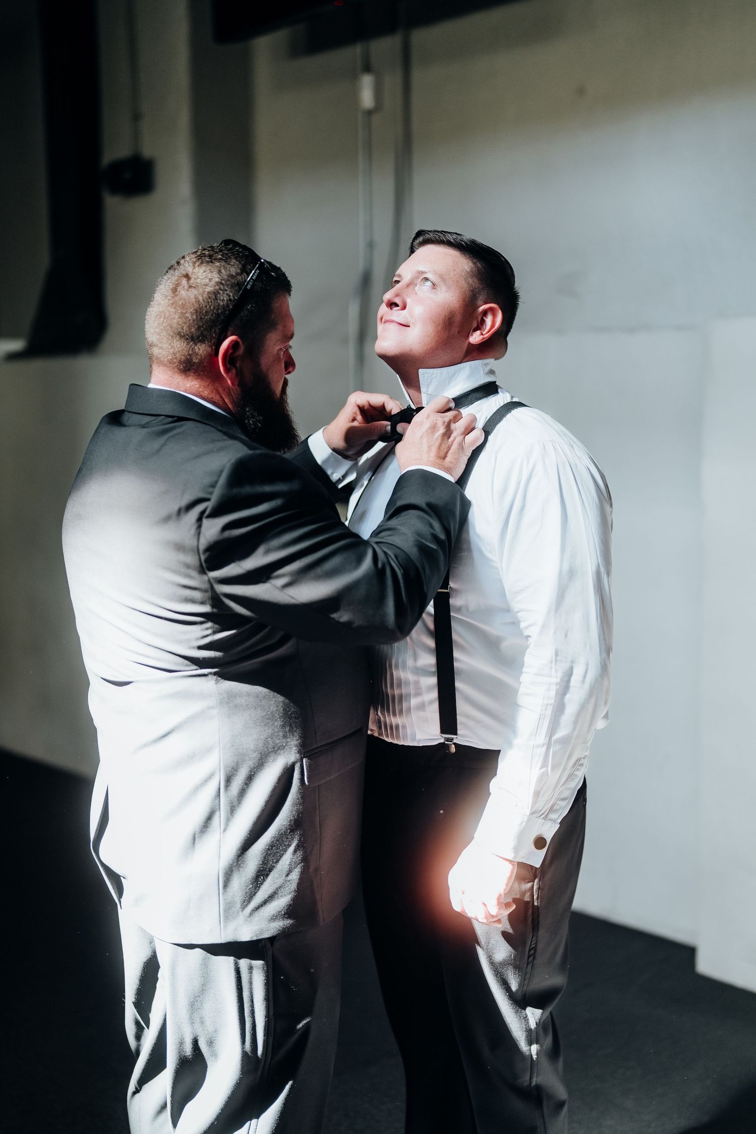 Emotional first look sequence between two people in formal attire against a white wall.