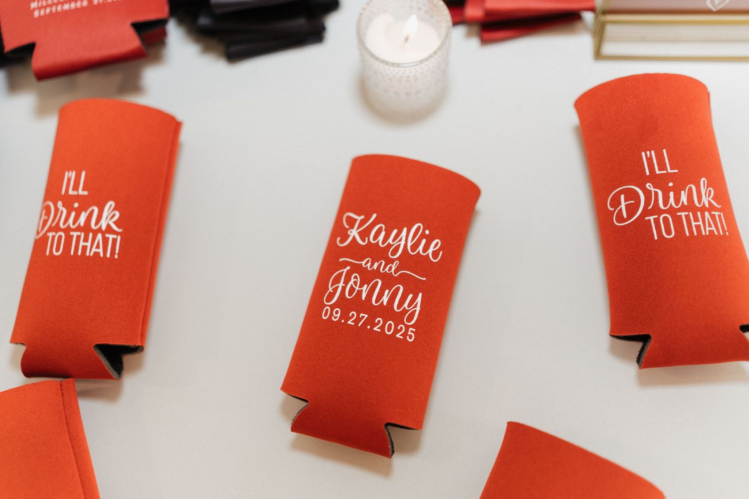 Red drink koozies with white text displayed as wedding favors.