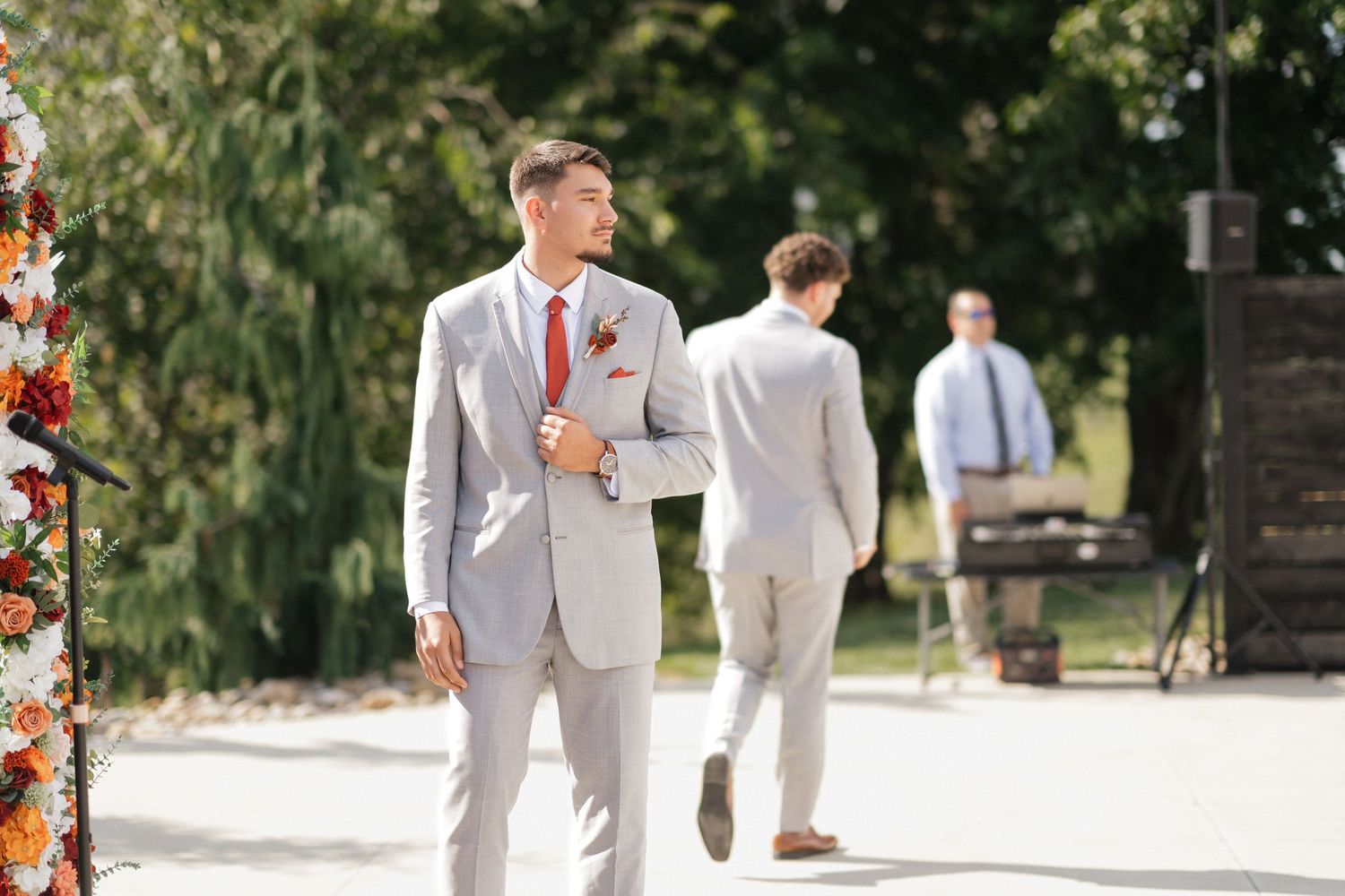 Wedding party in light gray suits walking outdoors on a sunny day.