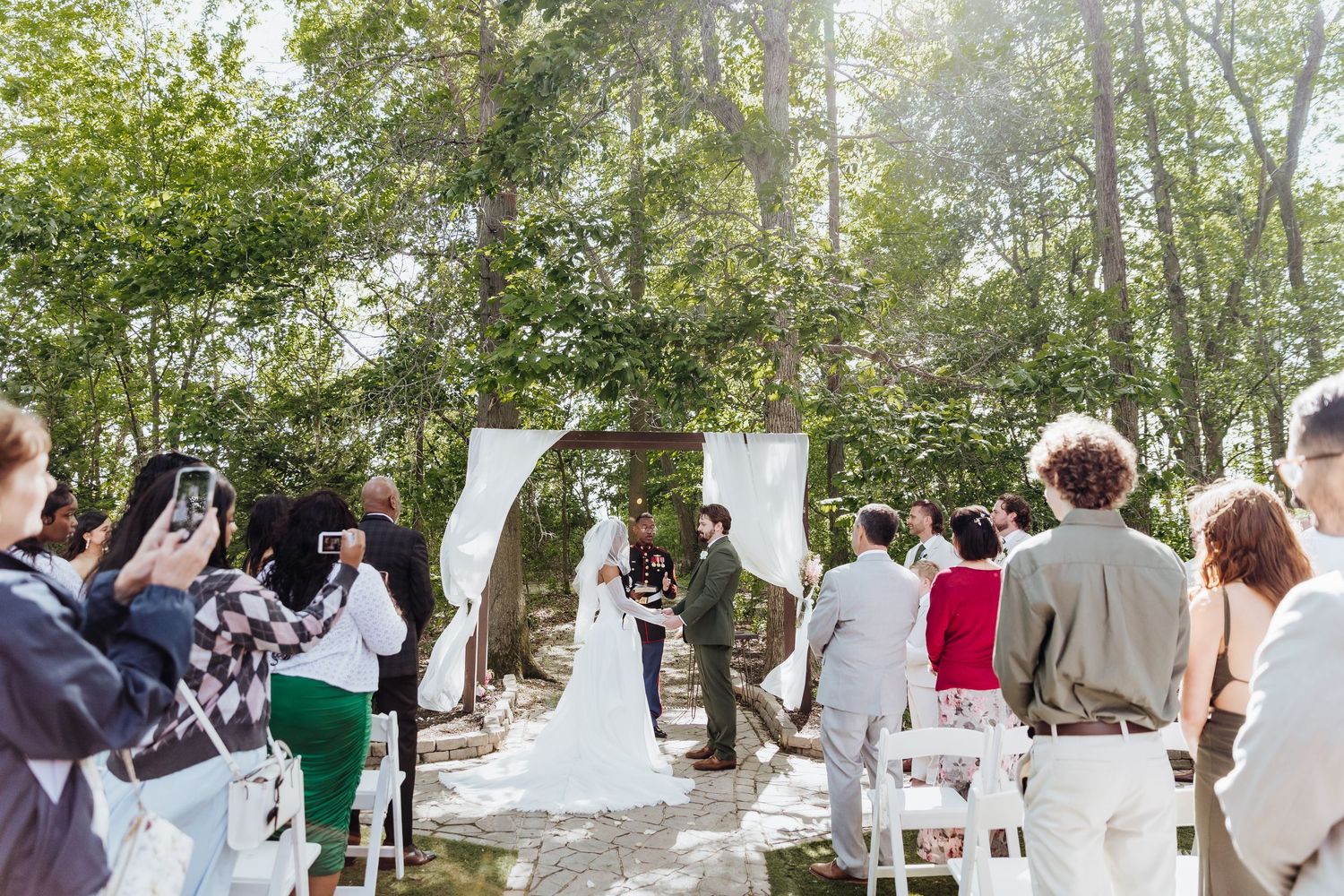 Wedding guests seated in white chairs for an outdoor ceremony.