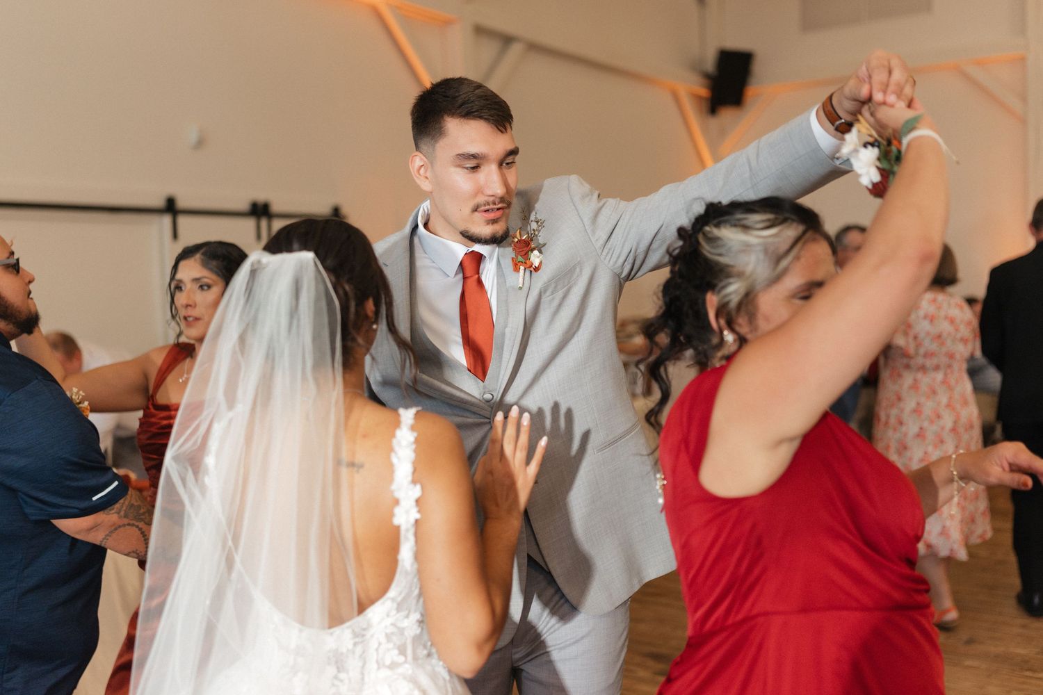 Wedding party dancing and celebrating at an indoor reception.